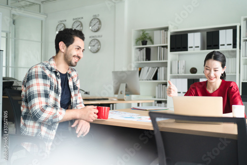 Happy and relaxed office workers discuss new project or work plan document casually on the office desk, the concept of teamwork, working lifestyle, positive healthy working, creative meeting teamwork