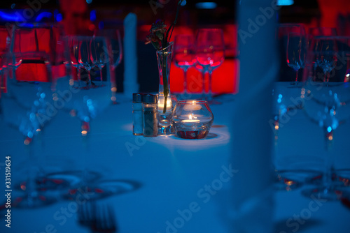 A small romantic candle standing in the middle of a banquet table giving the surroundings discreet lighting.