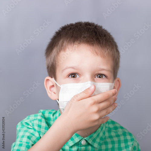 Boy in a medical mask on a gray background