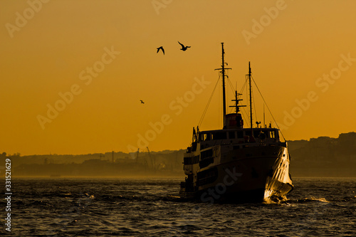 City passenger ship in silhouette going on the water when sunset time in the Istanbul of Turkey.