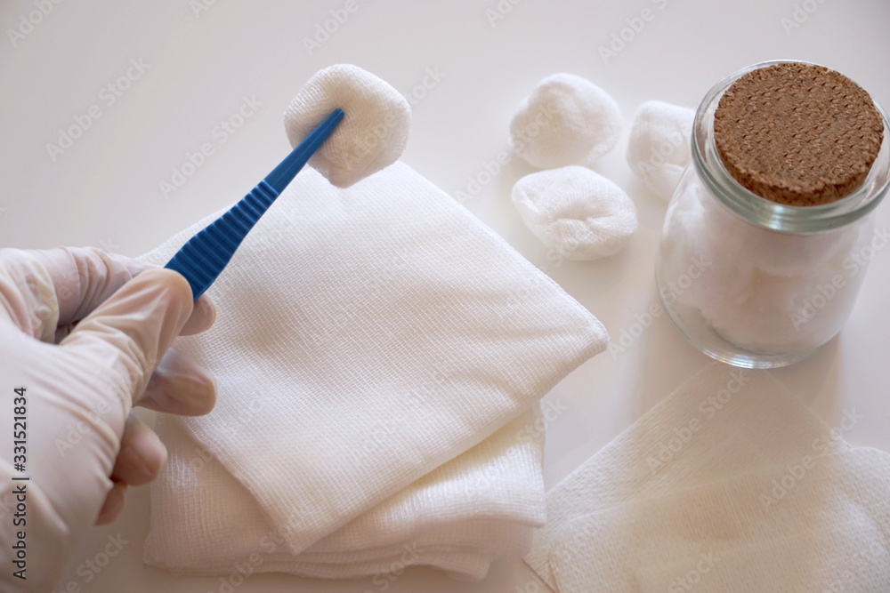 Balls made of gauze. Sterile white piece of gauze on a medical forceps in the doctor hand Balls made of gauze. Sterile white piece of gauze on a medical forceps in the doctor hand