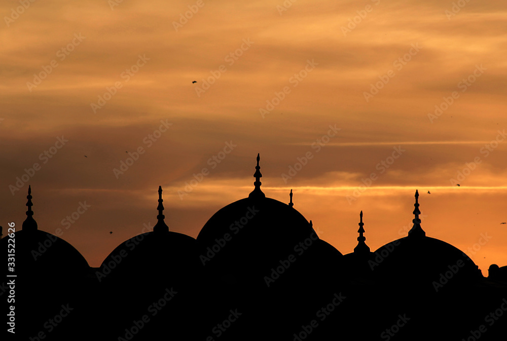 Domes of the Valide Sultan Mosque in line when sunset in Istanbul of Turkey.Silhouette and Ramadan concept.