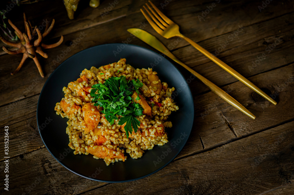 Bulgur with pumpkin on a wooden table. Vegetarian recipes from Indian cuisine. Bulgur with pumpkin on a wooden table. Vegetarian recipes from Indian cuisine.