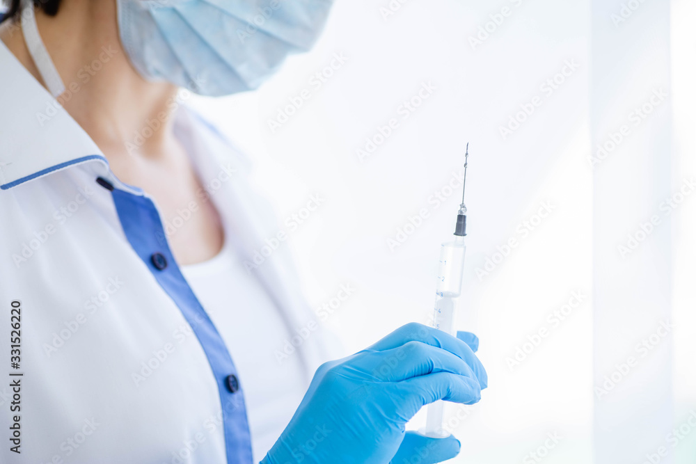 Female doctor or nurse in medical mask holding syringe with injection Female doctor or nurse in medical mask holding syringe with injection