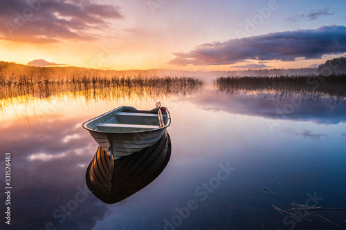 Boat on still lake at sunrise, Sweden. photo