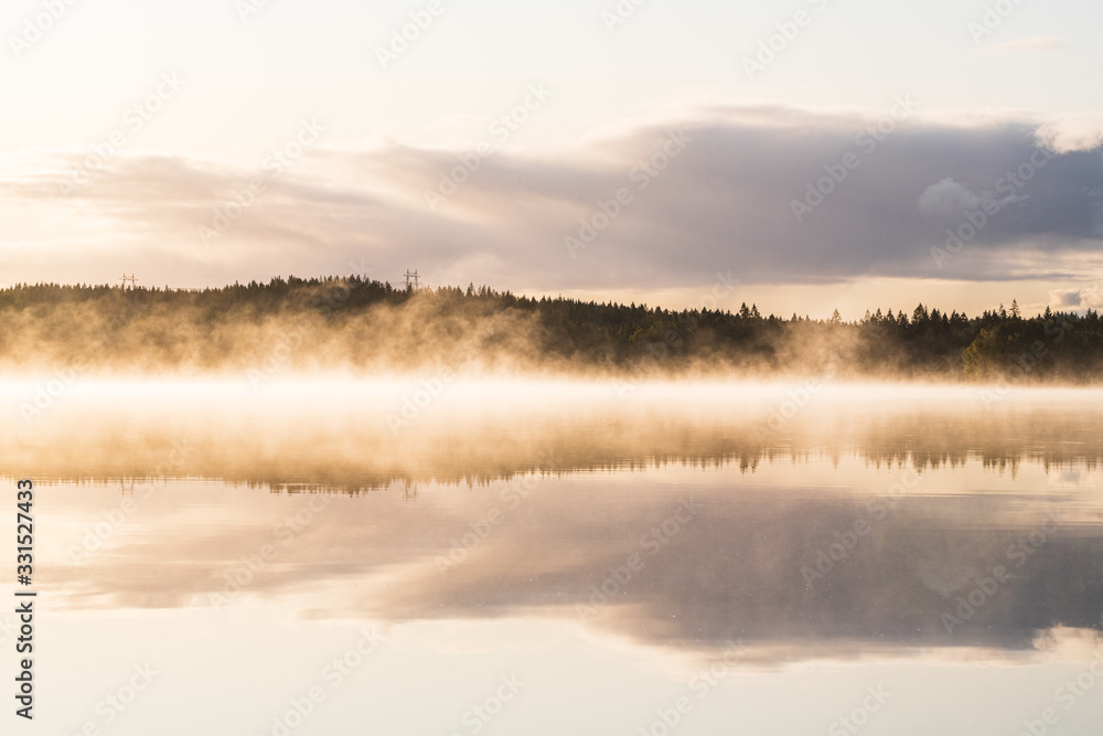 Fototapeta premium Mist and reflections on a calm lake, Sweden.