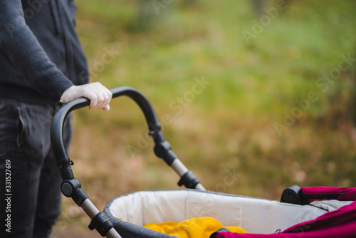 A man on a walk with a baby troller and hands in gloves