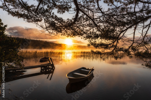 Row boat on still lake at sunrise
