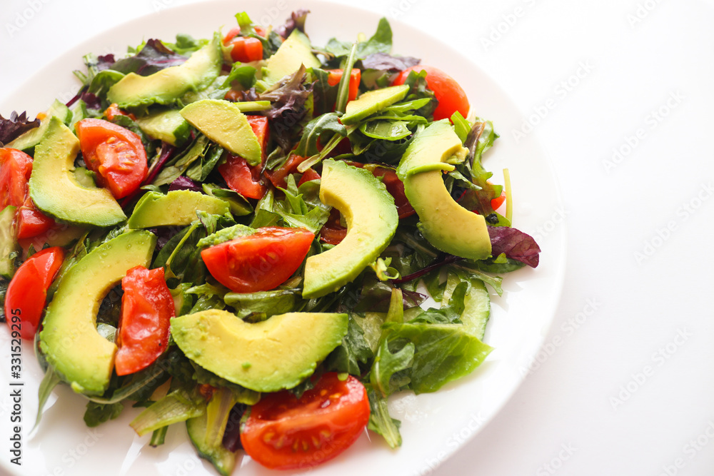 Healthy food, fresh salad with avocado and cherry tomatoes on a white plate. Food concept, veggie salad, vegetarian food Healthy food, fresh salad with avocado and cherry tomatoes on a white plate. Food concept, veggie salad, vegetarian food