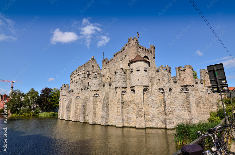 Ghent, Belgium, August 2019. The Gravensteen is the castle of the counts of Flanders. View from the side of the moat: the imposing medieval structure. Sunny day.
