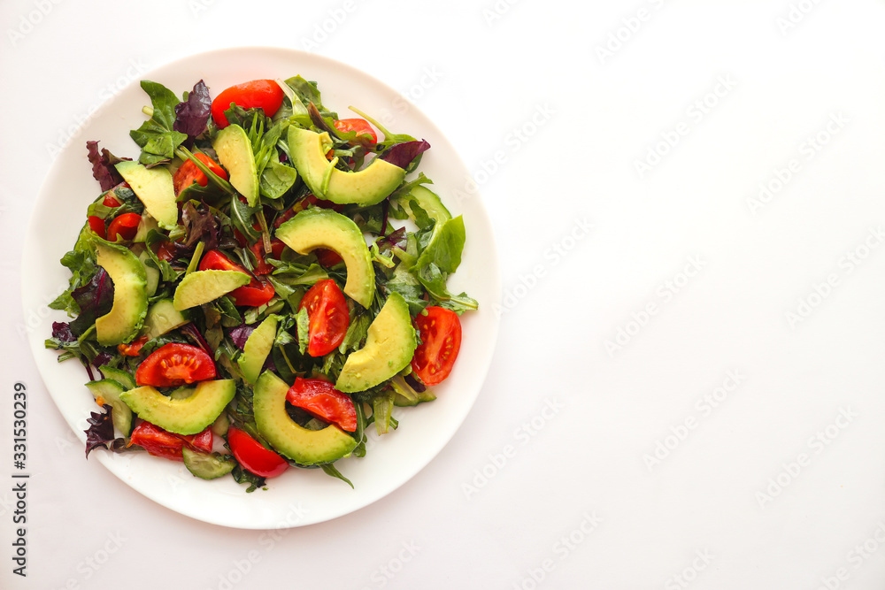 Fresh salad with avocado and cherry tomatoes on a white plate. Food concept, veggie salad, vegetarian and healthy food