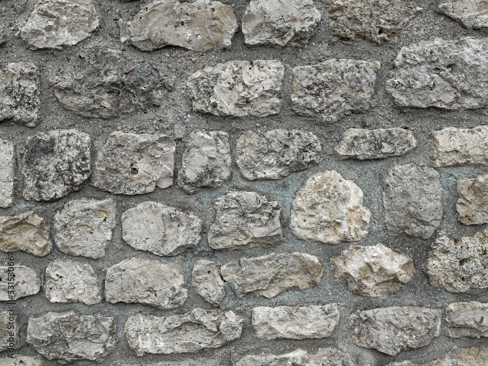 wall composed of large old stones sealed in grey concrete wall composed of large old stones sealed in grey concrete