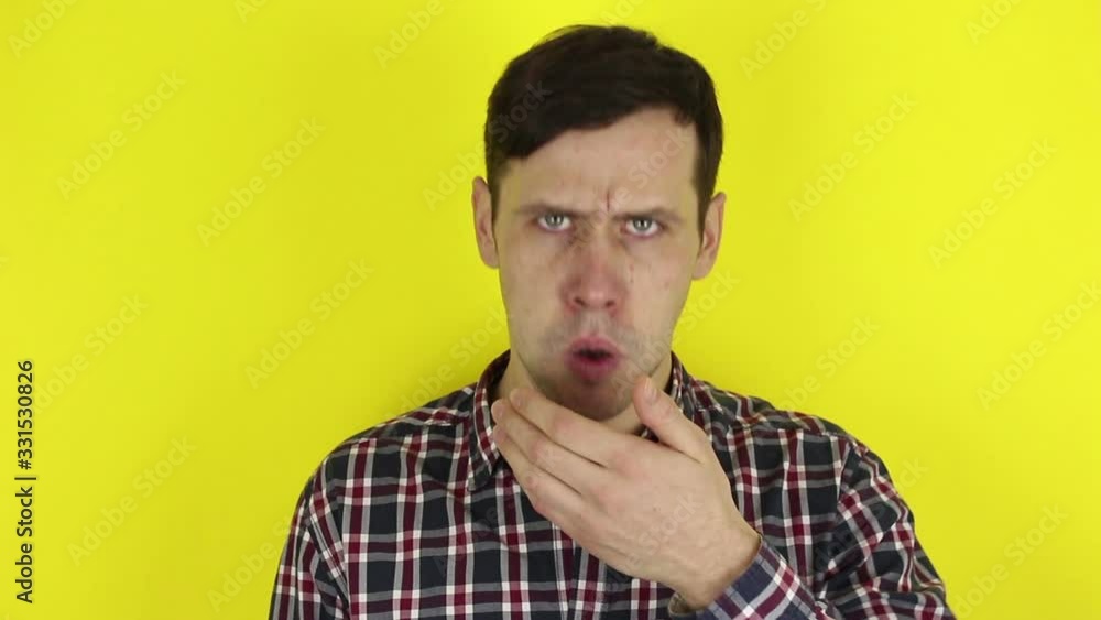 A funny, pretty guy, coughs hard and covers his mouth with his hand. Portrait of a young guy, he coughs violently from a cold and covers his mouth with his hand. Portrait on a yellow background. A funny, pretty guy, coughs hard and covers his mouth with his hand. Portrait of a young guy, he coughs violently from a cold and covers his mouth with his hand. Portrait on a yellow background.