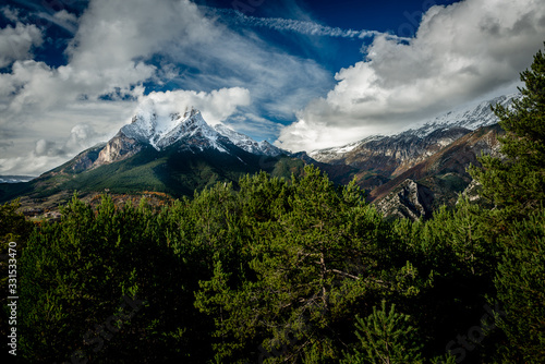 Montaña con nieve en la cima, cielo azul y nubes blancas