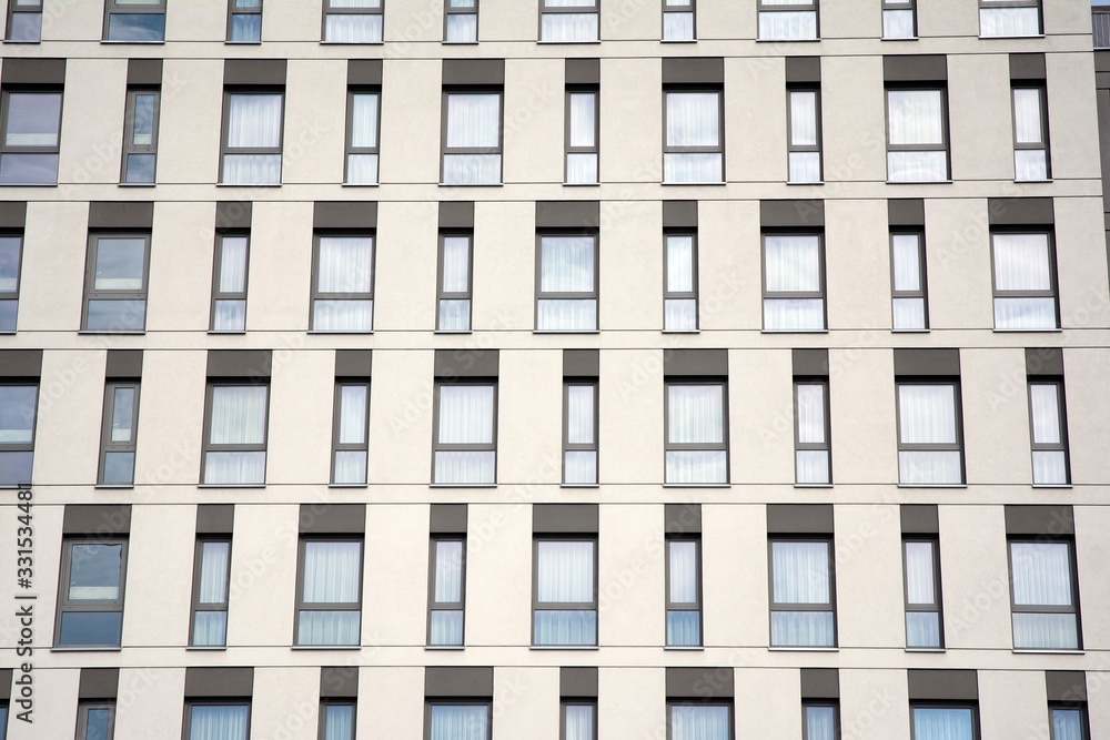 A view at a straight facade of a modern building with a dark grey facade. Dark grey metallic panel facad. Modern architectural details. A view at a straight facade of a modern building with a dark grey facade. Dark grey metallic panel facad. Modern architectural details.
