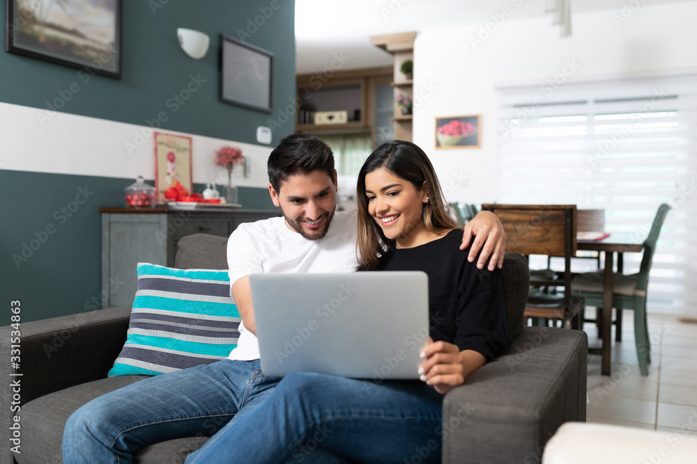 Smiling Couple Using Laptop At Home Smiling Couple Using Laptop At Home