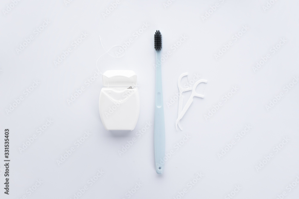 Flat lay composition of blue toothbrush, dental floss and toothpicks on a white background. Flat lay composition of blue toothbrush, dental floss and toothpicks on a white background.