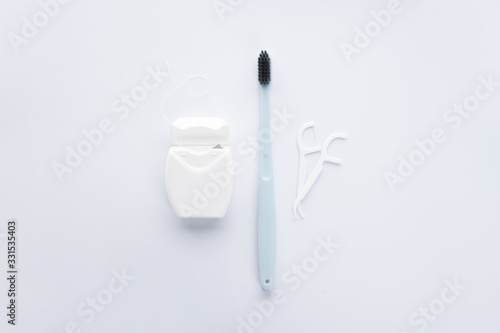 Flat lay composition of blue toothbrush, dental floss and toothpicks on a white background. © VI Studio