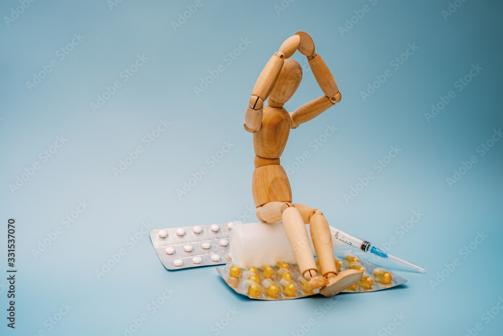 The wooden figure sits next to the pills.
