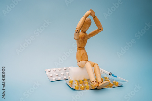 Obraz na płótnie The wooden figure sits next to the pills. w salonie