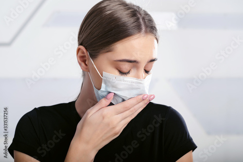 A girl sick with a new coronavirus coughs in a disposable facial mask. Epidemic corona virus. Covid-19 protection. Quarantine all over the world. White background