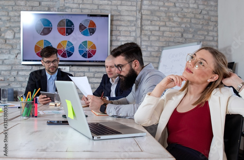 Team of young business people and designers working in a modern retro style office. Beautiful young business woman daydreaming in front of her laptop. Startup concept.