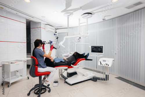 The dentist looks through a microscope and performs surgery on the patient