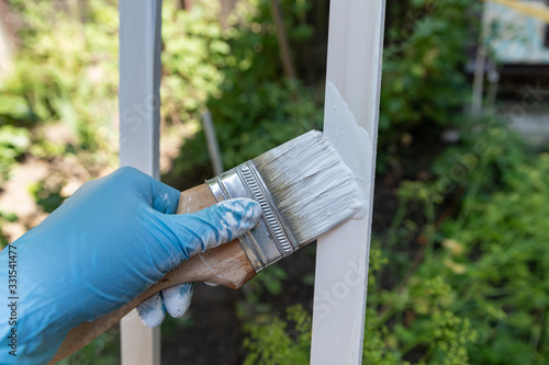 Wallpaper Mural paint brush covered with white paint in hand and paint can paint wooden planks on the dark background in the yard Torontodigital.ca