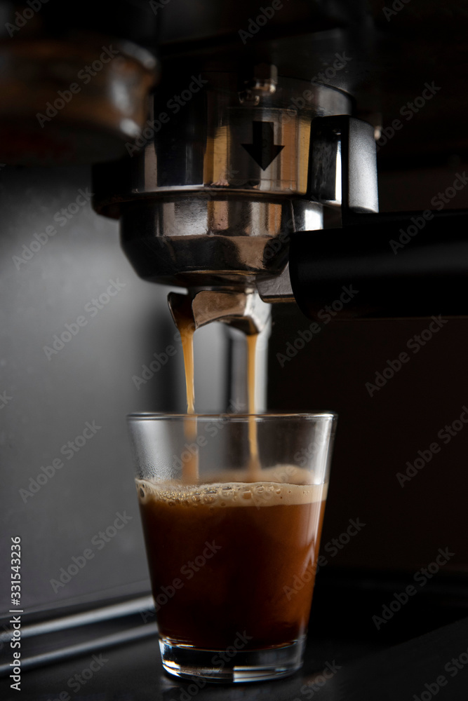 Close-up of a coffee machine pouring coffee into cups