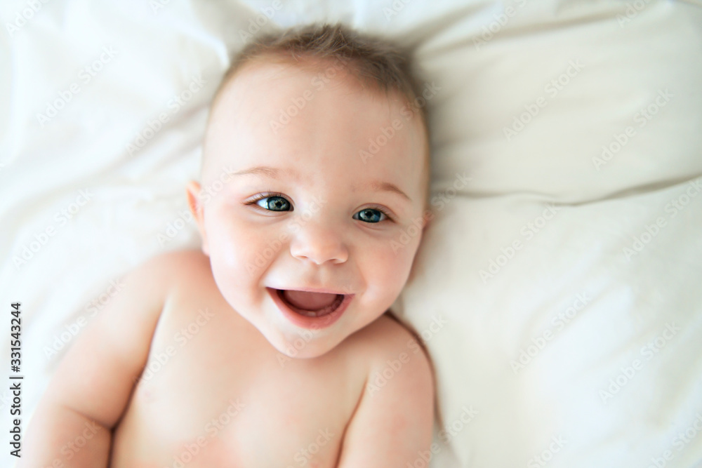 cute baby boy lying on a white bed