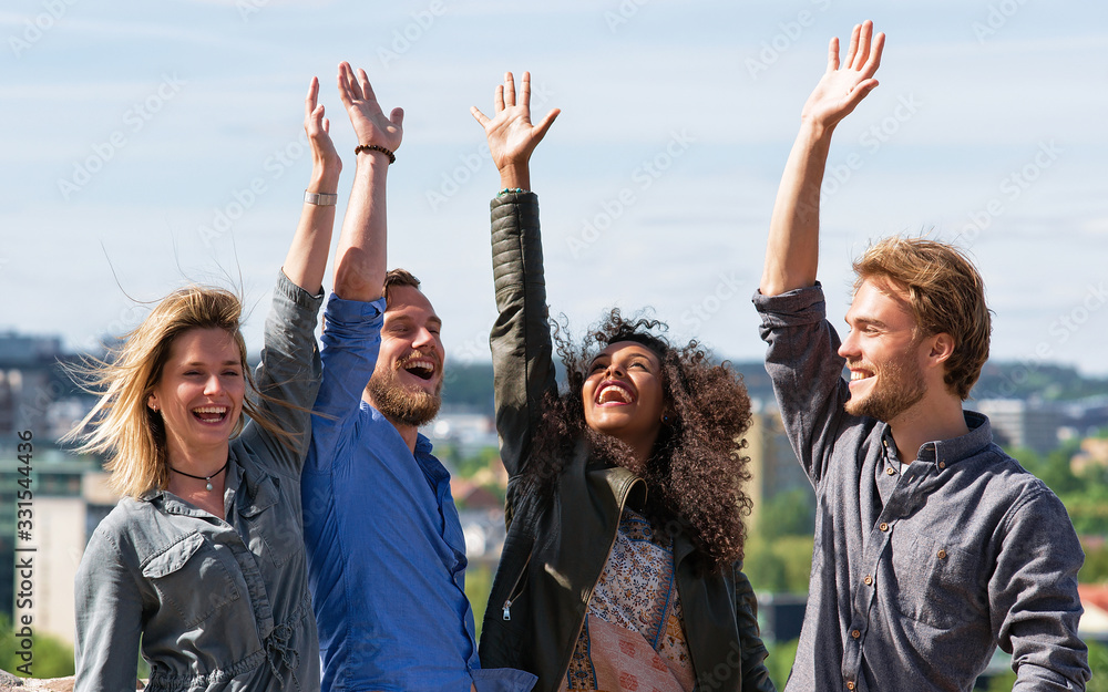 Group of young friends raising their hands up Group of young friends raising their hands up