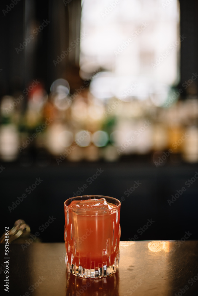 Cocktail in a rocks glass decorated with a dried slice of peach. Dark background. Smooth image with shallow depth of field.