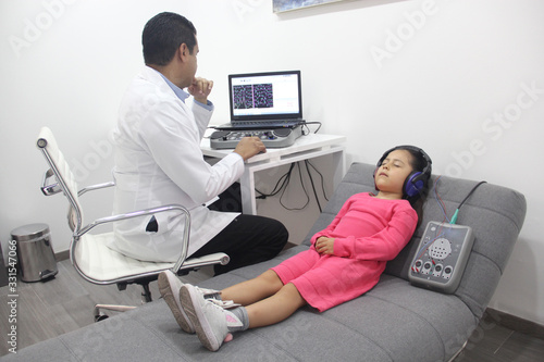 Foto Examen medico auditivo a niña con doctor