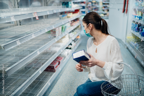 Woman wearing face mask buying in supermarket/drugstore with sold-out supplies.Preparation for a pandemic quarantine due to coronavirus covid-19 outbreak.Hygiene, cleaning and disinfection products.