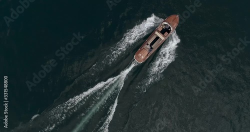 old mahogany motor boat is sailing along Garda Lake in Italy. Aerial shot.