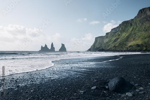 black sand beach with strange rock formations in sea