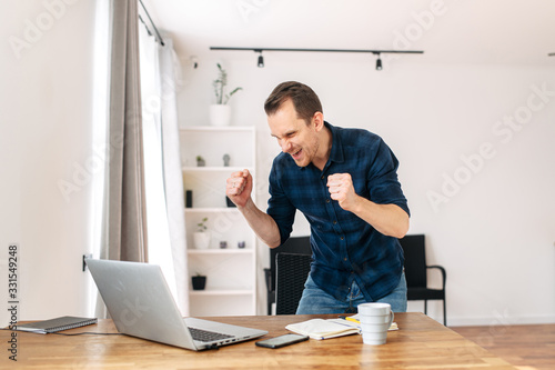 A man looks at laptop and rejoices at job success
