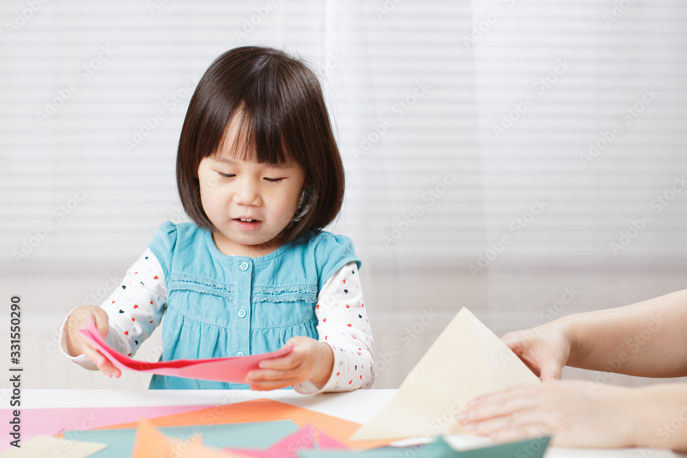 toddler girl learn making Origami at home against white background toddler girl learn making Origami at home against white background