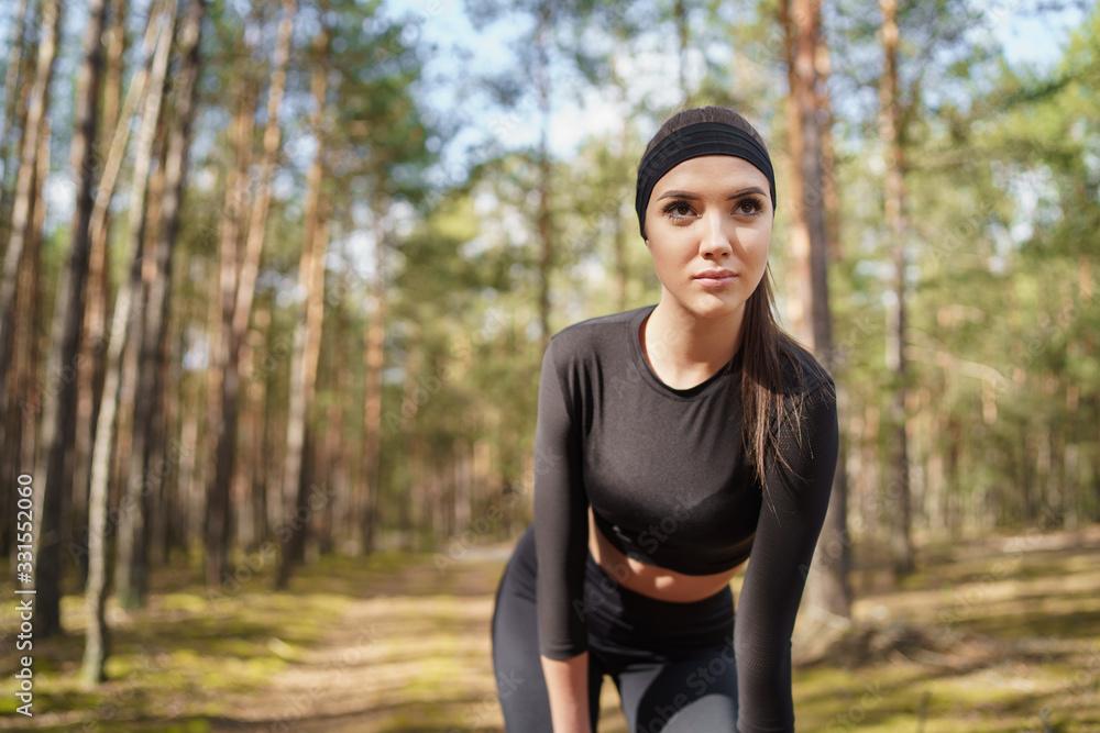 Young woman doing warm-up before running in forest. A teenager prepares to run on forest paths. Natural forest light. Young woman doing warm-up before running in forest. A teenager prepares to run on forest paths. Natural forest light.