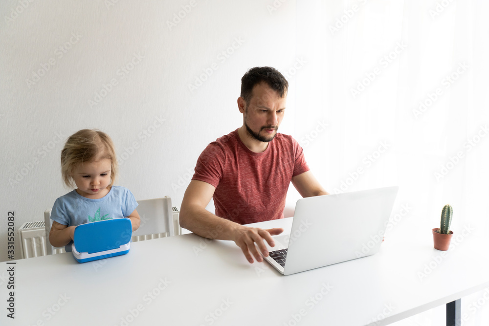 Young caucasian man, father should work from home during quarantine time at coronavirus. Child at home, kindergarden closed. Baby helps father to work. They work in laptops. White background. Young caucasian man, father should work from home during quarantine time at coronavirus. Child at home, kindergarden closed. Baby helps father to work. They work in laptops. White background.