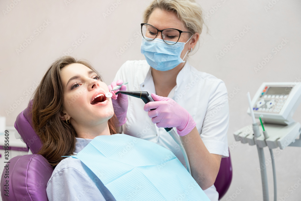 Woman dentist curing patient teeth with instrument. Woman dentist curing patient teeth with instrument.