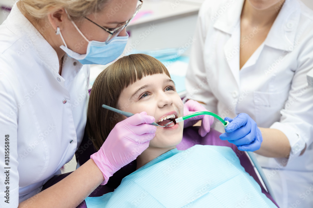 Dentist and assistant examining kid mouth with dentistry equipment instrument. Dentist and assistant examining kid mouth with dentistry equipment instrument.