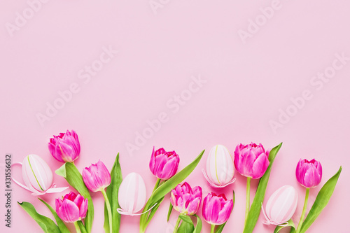 Fototapeta Naklejka Na Ścianę i Meble -  Easter background. Decorative pink Easter Eggs and tulip flowers on pink background. Top view, copy space. Easter celebration concept.