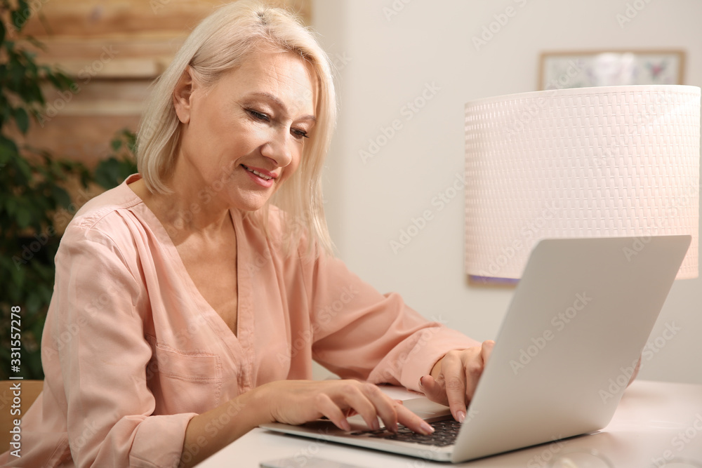 Beautiful mature woman working with laptop at home Beautiful mature woman working with laptop at home