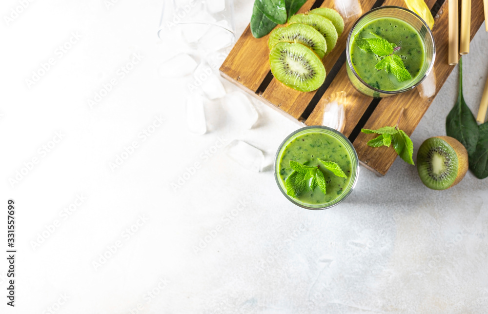 Detox green smoothie - kiwi, spinach and matcha on a light grey slate, stone or concrete background. Detox green smoothie - kiwi, spinach and matcha on a light grey slate, stone or concrete background.