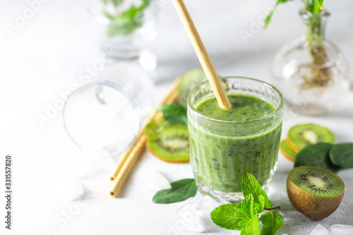 Detox green smoothie - kiwi, spinach and matcha on a light grey slate, stone or concrete background.