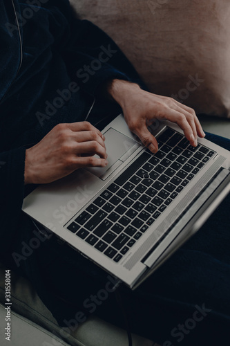 Self distancing from people. Work at home. Home office. Male works at home using laptop. Stay home on weekdays in robe and pajama. Mens hands on the laptop.