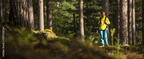 Foto Pretty, young female hiker walking through a splendid old pine forest (shallow D