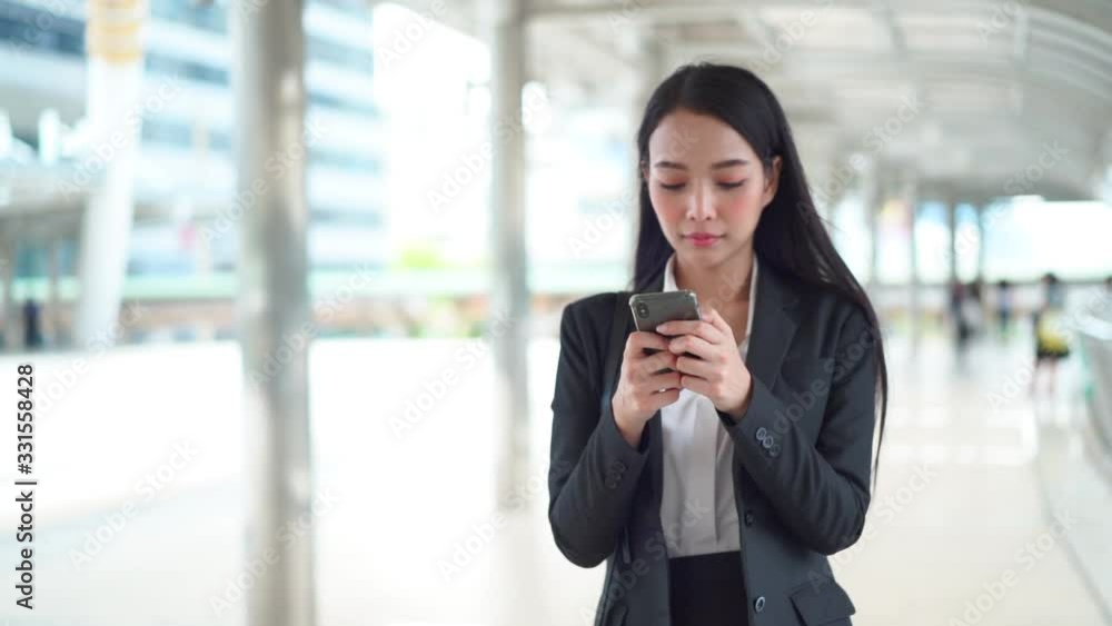 Slow motion shot of young Asian young business woman receive good news from email and dancing victory dance in the business district Slow motion shot of young Asian young business woman receive good news from email and dancing victory dance in the business district