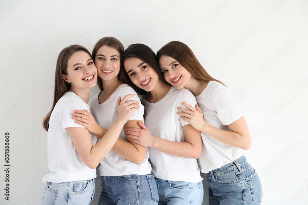 Beautiful young ladies in jeans and white t-shirts on light background. Woman's Day Beautiful young ladies in jeans and white t-shirts on light background. Woman's Day